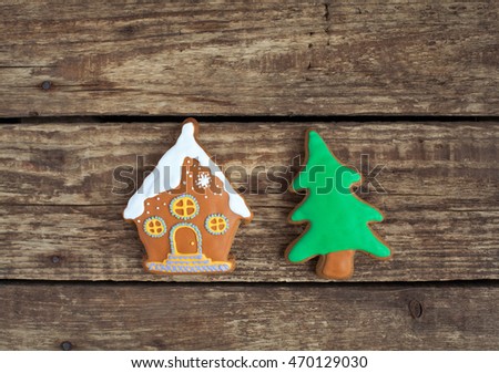 Homemade gingerbread cookies in the shape of house with snow, Christmas tree on the wooden table. Space for text and selective focus.
