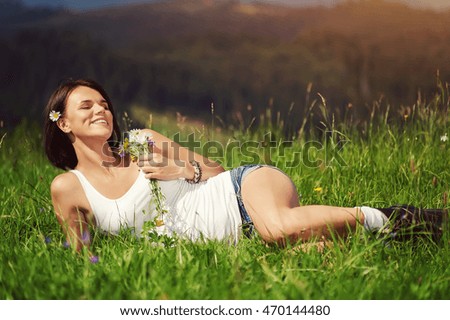 beautiful happy girl dressed in country style smiling and  lies on field of grass