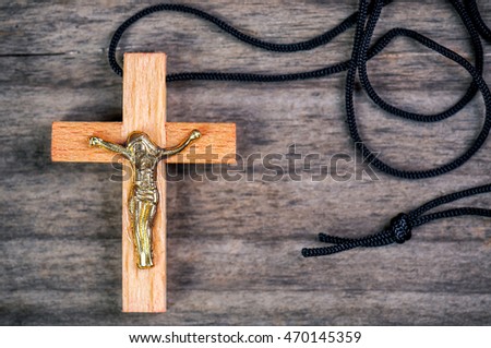 holly wooden Christian cross with black rope on wooden background
