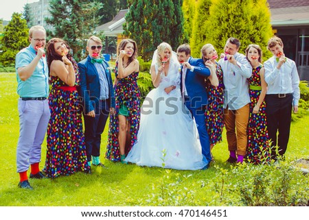 Wedding couple and friends pose on the lawn while eating sugar candies