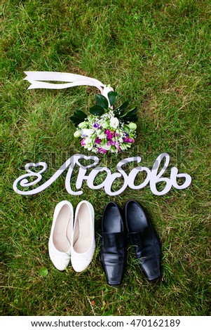 Beautiful wedding bouquet, shoes and sign with russian text "LOVE" on green lawn