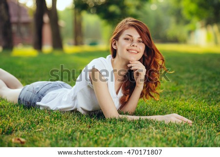 The red-haired girl enjoying the outdoors and the warmth lying on the grass