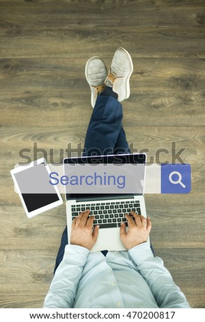 Young man sitting on floor with laptop and searching SEARCHING concept on screen