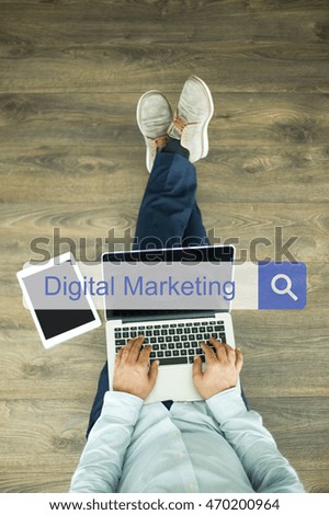 Young man sitting on floor with laptop and searching DIGITAL MARKETING concept on screen
