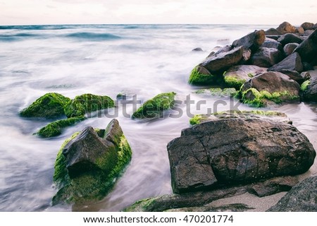A coastline with big stones in the water. Motion photography. The stones are covered with moss. Pure nature.