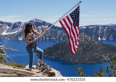 Woman holding American flag at Crater Lake, Oregon, USA
