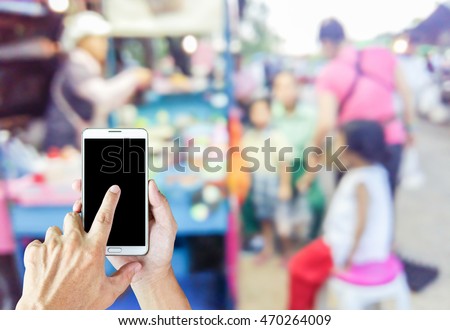 Man use mobile phone blur image of kids buying sweet as background.