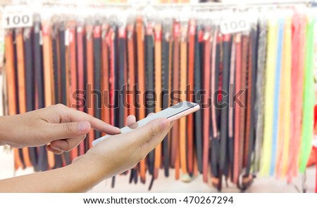 Man use mobile phone, blur image of belt shop as background.