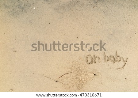 written words "Oh baby" on sand of beach