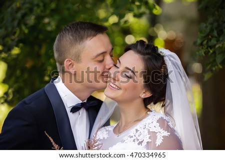 Wedding day. Groom kisses the bride on the park on the wedding day. Portrait of bride and groom. Kissing wedding couple. Wedding concept