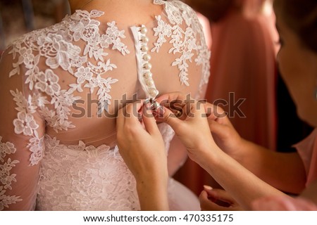 Wedding. Bridesmaid preparing bride for the wedding day. Bridesmaid helps fasten a wedding dress the bride before the ceremony. Luxury bridal dress close up. Best wedding morning. Wedding concept Royalty-Free Stock Photo #470335175