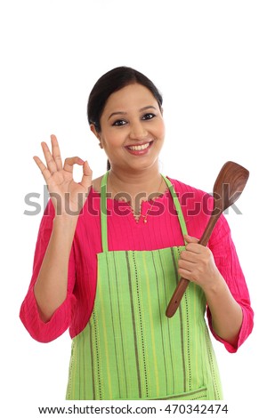 Happy young woman holding kitchen utensil against white background