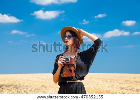 photo of the beautiful young woman with camera in the field