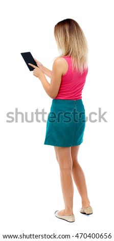 back view of standing young beautiful  woman using a mobile phone or tablet computer. girl  watching. Rear view people collection.  backside view of person.  Isolated over white background. Blonde in