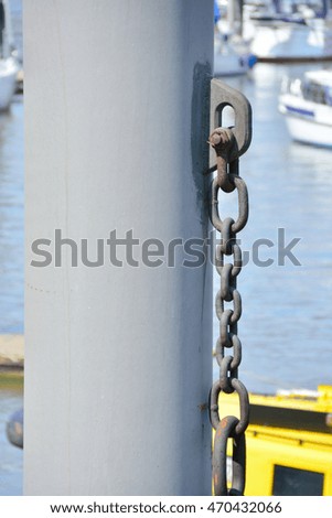 bollard and a chain on sea water and ships in the background
