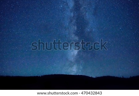 Night dark blue sky with many stars and milky way galaxy above a mountain