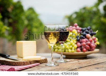 Wine on rustic wood table in vineyard.