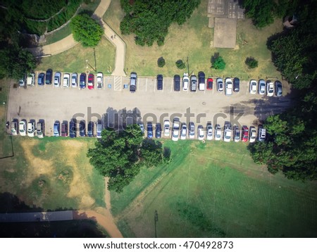 Aerial view of south parking lot in Zilker Metropolitan Park next to Barton Creek in Austin, Texas.  Rows of cars, road sign for disabled drivers with trees in busy summer day at outdoor park. Vintage