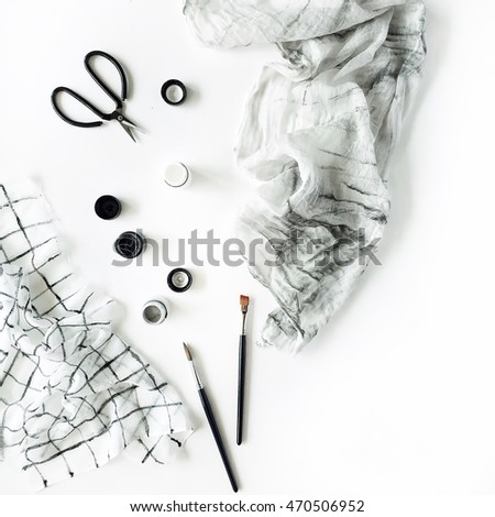 Watercolor, scissors, textile and brushes at white background. Flat lay, top view
