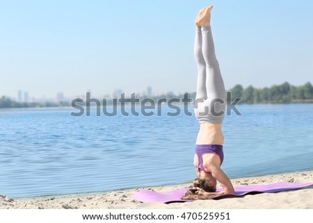 Attractive young woman doing yoga by the river
