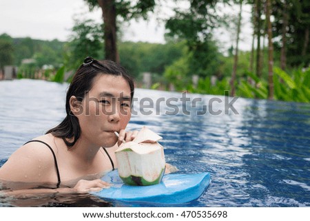 women drinking a coconut juice on  swimming pool