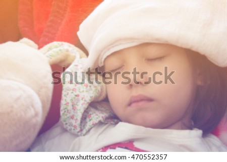 blurred picture of little girl getting sick and holding bunny doll 