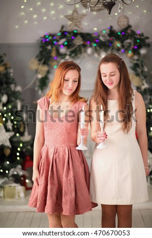 Two beautiful girls teenagers hold candles near christmas trees
