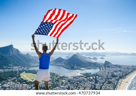 Athlete stands holding an American flag at a bright overlook of the city skyline of Rio de Janeiro, Brazil