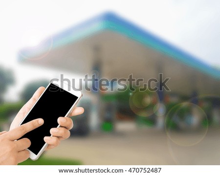 woman use mobile phone and blurred image of gas station