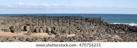 Panorama of the calm Indian Ocean waves breaking on grey weathered  basalt rocks at  Ocean Beach Bunbury Western Australia on a fine sunny  morning in late winter  are cool and refreshing.