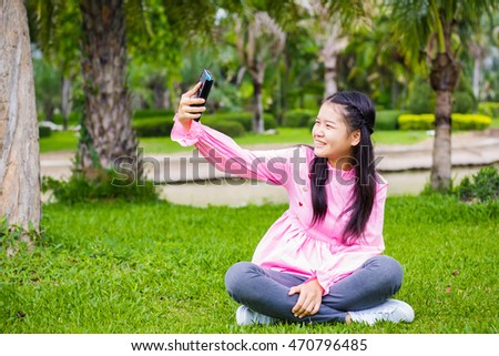  asian cute girl holding camera in hand and take a picture with selfie shot in park