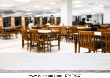 Empty wooden desk space platform with library background for product display.