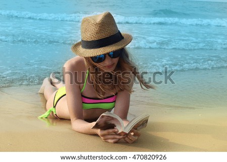 young girl reading a book on the beach