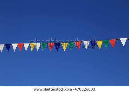 close-up of various multi-colored festive flags on a blue sky background the sky