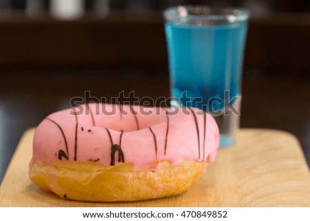 donuts with cocktail glass Blue Hawaii on wood.