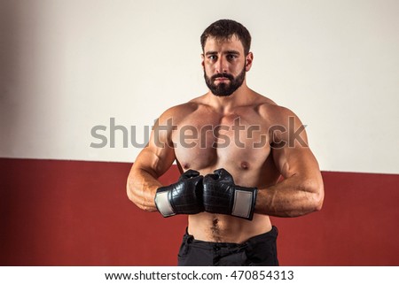Muscular boxer in boxing gloves is looking at the camera. 
