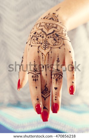 Red manicured hands with Mehndi 