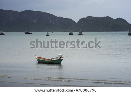 Traditional fishing  boat laying on a beach near the sea with big and long mountain in background,cloudy sky,filtered image,high contrast picture style