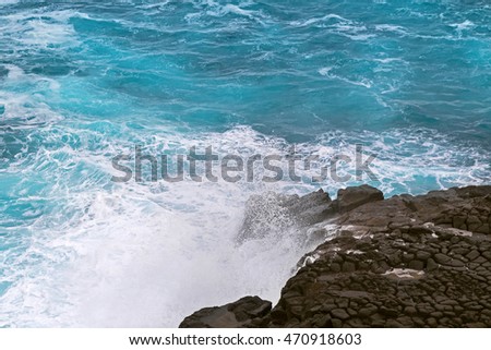 Deep blue sea water splashing volcanic rock at blowholes, rock tunnels, at Cape Bridgewater in Victoria, Australia
