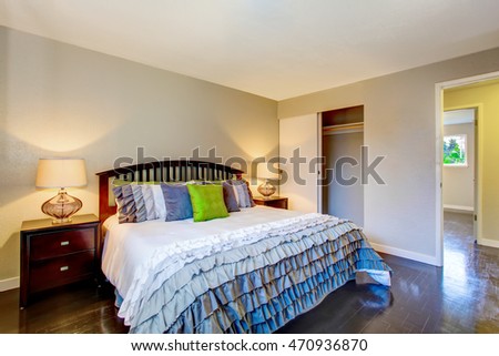 Bedroom interior with beige walls, deep brown hardwood floor and king size bed. Northwest, USA
