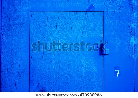 Big metal door with rusty cracked paint and dark lock. Deep blue metal door with cracked paint and dark vertical scratch. high resolution