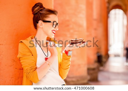 Young woman eating tiramisu, traditional italian dessert, on the street in Bologna city in Italy. Tiramisu was invented in Veneto region in Italy. Soft focus with small depth of field