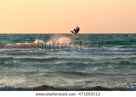 Man kiter riding on a beautiful background of spray and colourful sunset of mediterranean sea