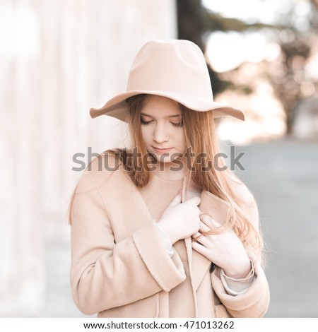 Stylish girl wearing beige winter coat and hat outdoors. Fashionable. 20s.