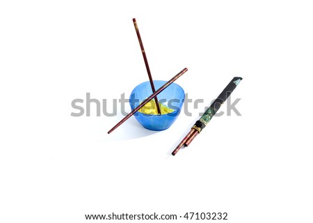 Some rice in a cup with sticks on a white background.