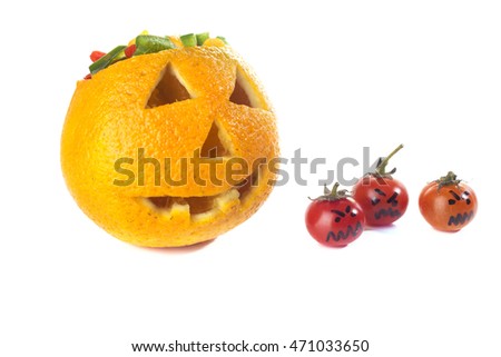 Food art creative concept. Halloween scary face carved into yellow orange fruit with capsicum vegetables brain and sweet tomatoes monsters isolated over a white background