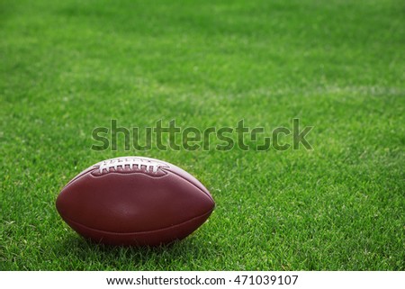 American football ball on a green grass