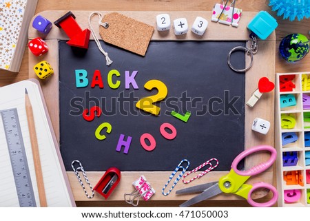 Small blackboard surrounded with various stationary with Back 2 School words in the middle, all on wood background