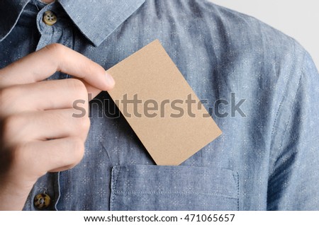 Kraft Business Card Mock-Up (85x55mm) - Man in a chambray shirt holding a kraft card on a gray background.
