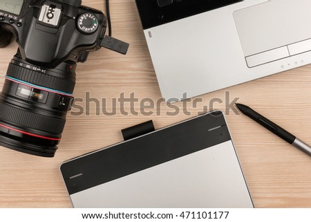 Working table of photographer or artist overhead view, wooden surface with laptop and camera